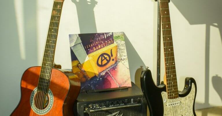 Close-up of acoustic and electric guitars with amplifier and musical notes indoors.